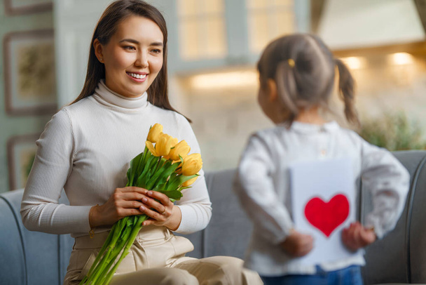 Happy mother's day. Child daughter congratulating her mother and giving her bouquet of flowers. - Zdjęcie, obraz