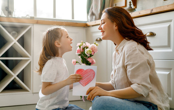 Happy mother's day. Child daughter congratulating her mother and giving her bouquet of flowers. - Фото, зображення