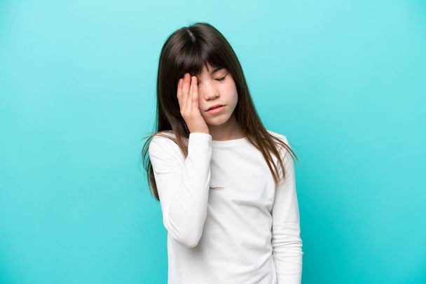 Little caucasian girl isolated on blue background with headache - Фото, изображение
