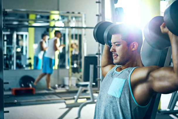 You can do it. a man doing a upper-body workout at the gym - Photo, Image