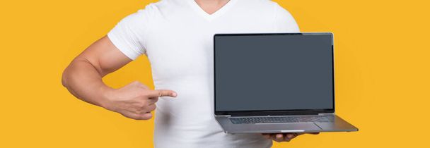 man showing screen isolated on yellow background, point finger. man showing screen in studio. man showing screen of laptop. man showing screen with copy space. - Photo, Image
