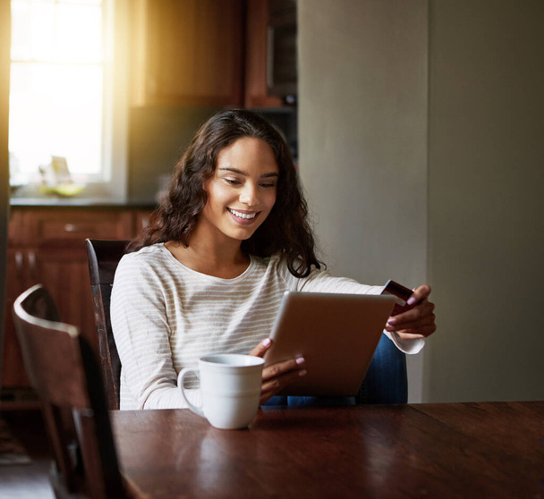 Terapia detaliczna ułatwiona dzięki e-commerce. młoda kobieta pije kawę i robi zakupy online ze swoim tabletem cyfrowym w domu - Zdjęcie, obraz