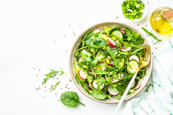 Ispanaklı yeşil salata, roka ve beyaz masada zeytinyağı ile turp. Kopyalama alanı olan üst görünüm. - Fotoğraf, Görsel