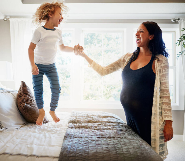 Guardami fare il salto in alto ora. una donna incinta legare con il suo piccolo figlio a casa - Foto, immagini