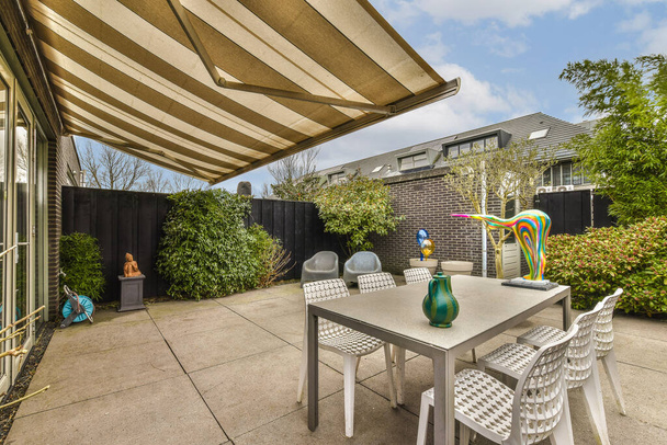 a patio area with a table and chairs under an awning over the outdoor dining set for two people to enjoy - Photo, Image
