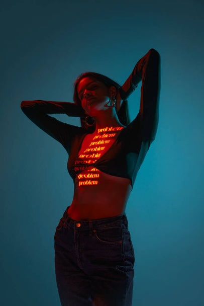Online relationship. Futuristic style portrait of young woman with digital neon filter lights on clothes over blue background. Concept of art, fashion, cyberpunk, futurism, modern and creativity. - Foto, Imagen