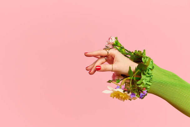 Spring Fashion week. Porträt mit eleganter weiblicher Hand, die Blumen im Ärmel über rosa Studiohintergrund hält. Konzept der Natur, Blütezeit, stilvolle Kleidung, Schönheit, Kunst, Kreativität, Werbung - Foto, Bild