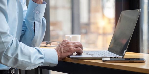 Рука бизнесмена, работающего в Интернете, сосредоточена на мужских руках, печатающих на клавиатуре ноутбука в офисе. - Фото, изображение
