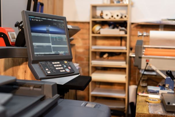 moderner Drucker neben Monitor und Knopfleiste im Druckzentrum  - Foto, Bild