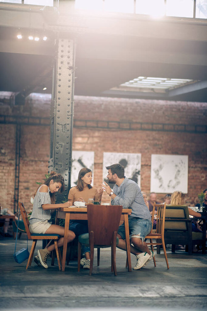 Young students on a coffee break, discussing something and writing. Learning, business, relaxation. - Foto, afbeelding