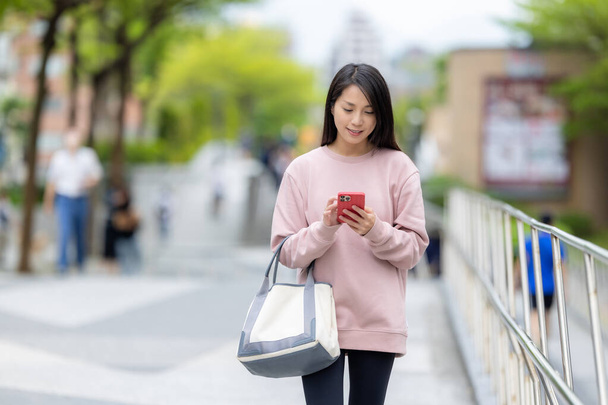 Nainen kävellä kadulla ja käyttää matkapuhelinta - Valokuva, kuva