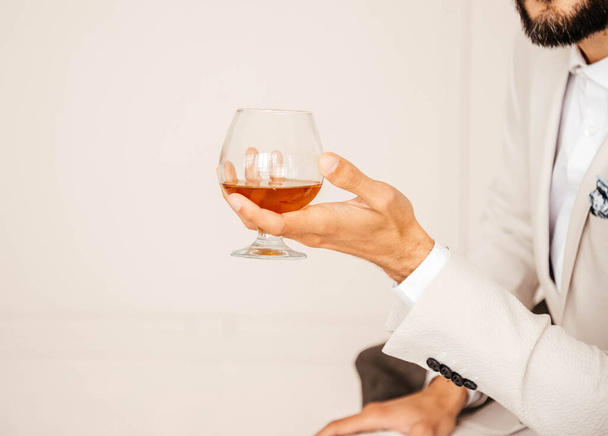 A glass of cognac in a mans hand.  - Фото, зображення
