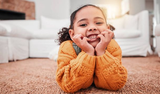 Child, portrait and girl kid lying on the floor in a home lounge or living room resting with a smile, happy and excited. Cute, relax and adorable of a young little female feeling happiness. - Foto, Imagen