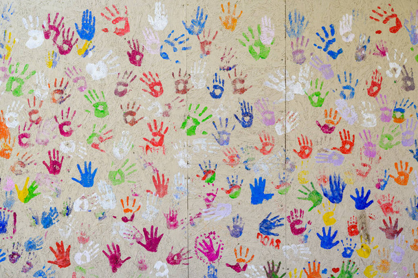otisky dětských rukou v pestrobarevné barvě na stěně, barevné otisky dlaní, záběr zblízka - Fotografie, Obrázek