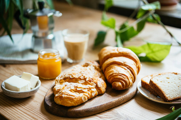 Breakfast with croissants and coffee served at a beautiful table full of plants. Enjoying time at home concept. - Foto, Bild