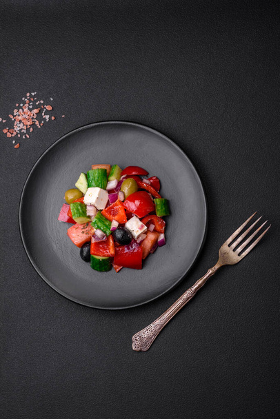 Delicious, fresh Greek salad with feta cheese, olives, tomatoes and cucumbers on a dark concrete background - Photo, Image