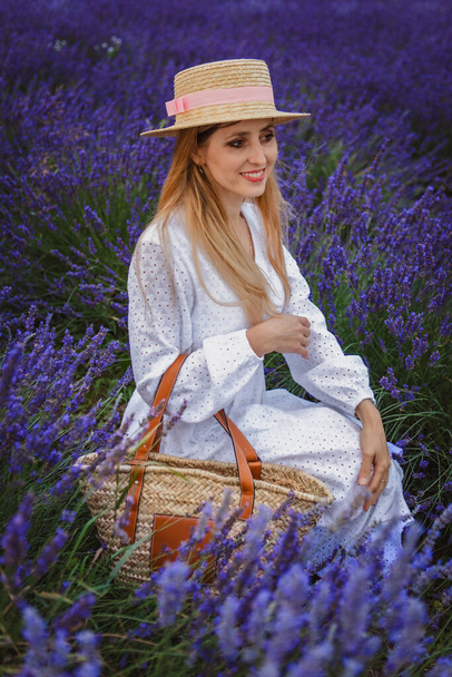 schöne Frau mit Hut und Tasche in der Hand in einem Lavendelfeld - Foto, Bild