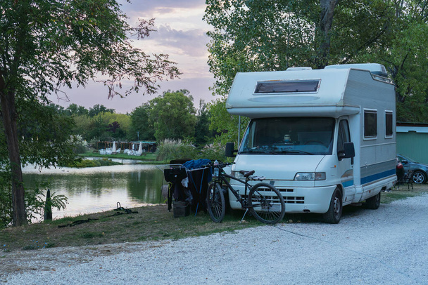 Polkupyörä matkailuauton vieressä, matkahuonekalut leirintäalueen vieressä aikaisin aamulla järven rannalla, perheloma, retkeilymatka, aito kestävyys, terve yhteys luontoon - Valokuva, kuva