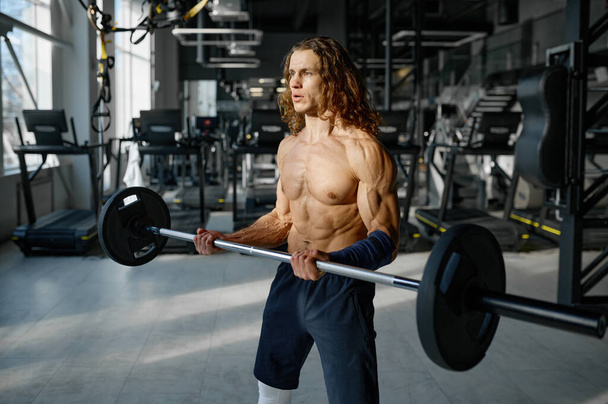 筋肉の完璧なボディを持つ強力なスポーツマンの肖像は、バーベルで演習を行う。ジムでのトレーニング - 写真・画像