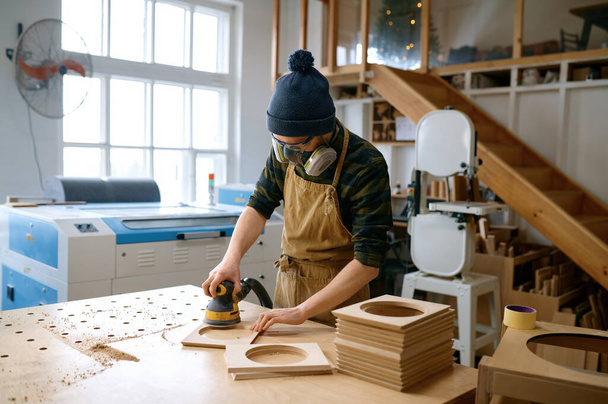 職場のベンチで働く偏心研削盤とプロの若い男の大工の研磨バー板。軌道測位の概念 - 写真・画像