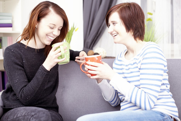 zwei glückliche Freundinnen mit Kaffeetassen  - Foto, Bild