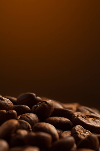 granos de café sobre un fondo oscuro con un toque amarillo en el fondo, granos de café de cerca para una cafetería. - Foto, Imagen