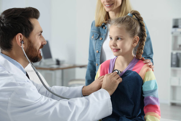 Mother and daughter having appointment with doctor. Pediatrician examining patient with stethoscope in clinic - Foto, Imagem