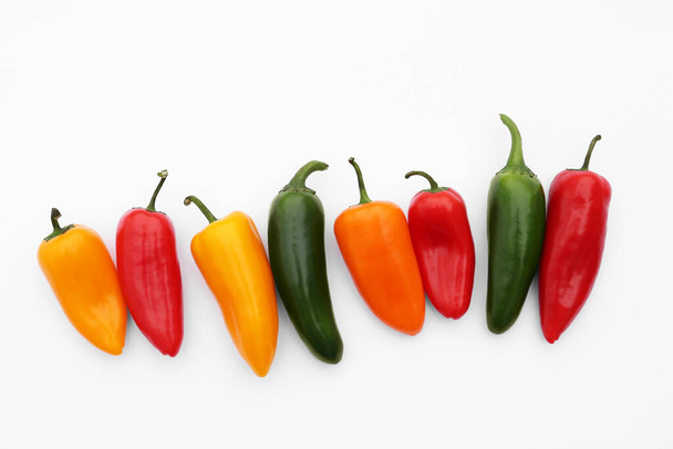 Verschillende hete chili paprika 's op witte achtergrond, plat gelegd - Foto, afbeelding