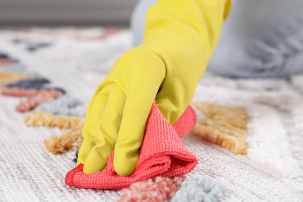 Woman in rubber gloves cleaning carpet with rag indoors, closeup - Foto, immagini