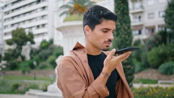 Closeup businessman speaking mobile phone at nature. Serious latina guy calling cell talking to assistant app at public park. Attractive brunette man recording voice message using smartphone outside  - Footage, Video