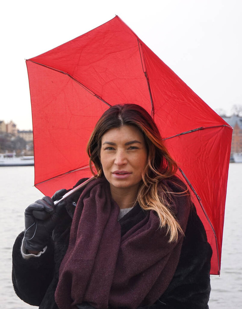 Portrait of woman with umbrella standing against canal during rainy season - Photo, image