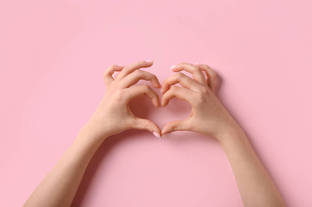 Γυναίκα που κάνει την καρδιά με τα χέρια της σε ροζ φόντο - Φωτογραφία, εικόνα