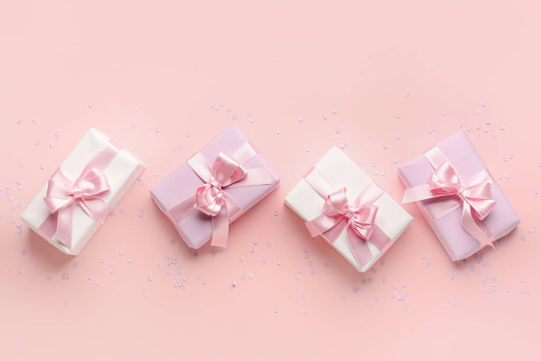 Κουτιά δώρου με όμορφα τόξα και κομφετί σε ροζ φόντο - Φωτογραφία, εικόνα