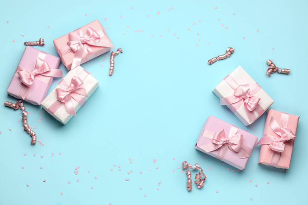 Frame made of gift boxes with bows, confetti and serpentine on blue background - Photo, Image