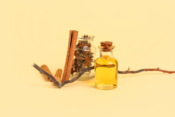 Μπουκάλι αιθέριο έλαιο με ξυλάκια κανέλας, γλυκάνισο και φόντο κλαδιού - Φωτογραφία, εικόνα