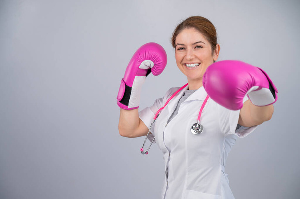 Γυναίκα γιατρός σε ροζ γάντια πυγμαχίας σε λευκό φόντο - Φωτογραφία, εικόνα
