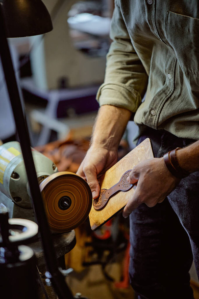 young man concentrated on working on electric burnishing tool. side view cropped portrait. amazing leather work, hobby, lifestyle, occupation, past time - Photo, Image