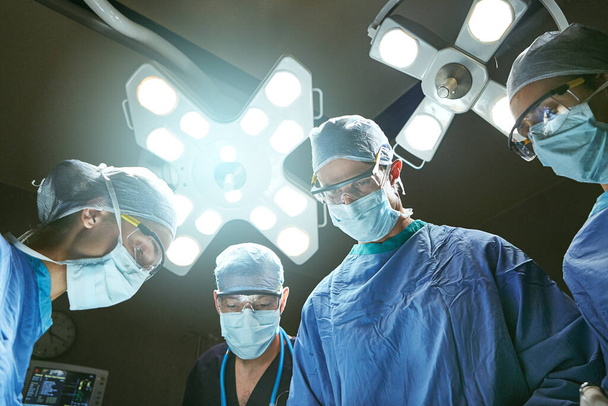 Gespecialiseerd in succesvolle operaties. Low angle shot van chirurgen in een operatiekamer - Foto, afbeelding