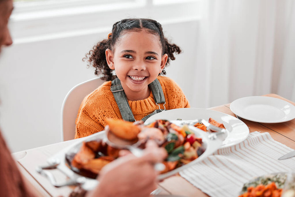 Family dinner, child and mother with vegetables serving at a home table with happiness on holiday. Food, house and happy eating of a girl with a smile at a gathering with a kid and mom at meal. - 写真・画像