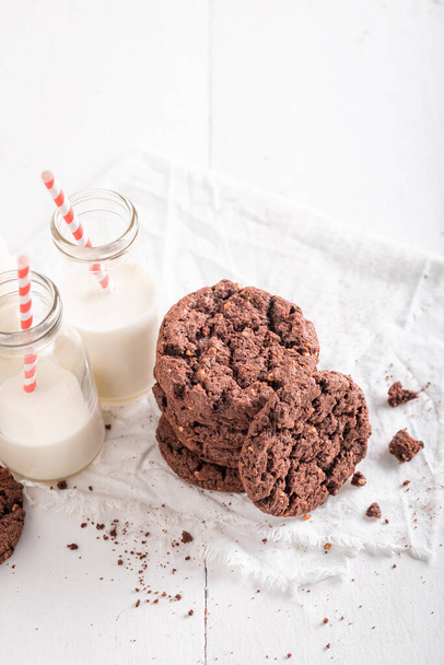Delicious brown cookies made with chocolate and nuts. Chocolate cookies with milk. - 写真・画像