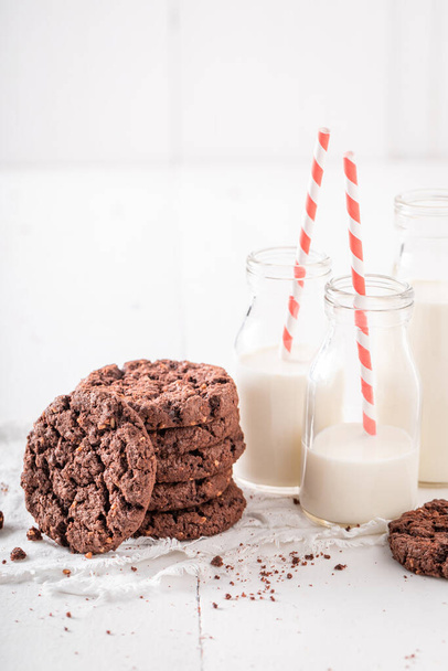 Delicious brown cookies served with milk in bottle. Chocolate cookies with milk. - 写真・画像