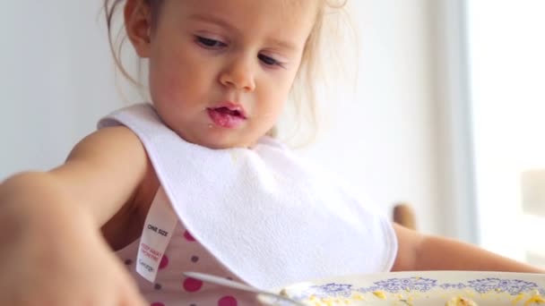 Caucasian little girl independently eats. Small child eats appetizing. Portrait of a child closeup that eats the food. - Felvétel, videó