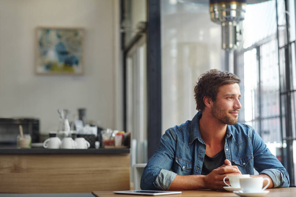 Contempler des choses autour d'un café. un beau jeune homme regardant réfléchi tout en prenant un café dans un café - Photo, image