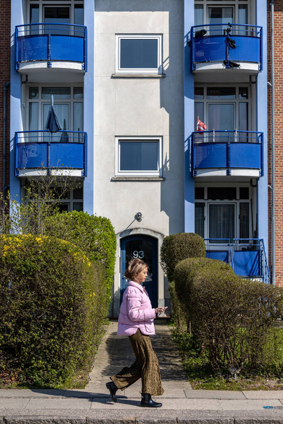 Kopenhaga, Dania Młoda kobieta spaceruje ulicą mieszkalną na przedmieściach Brondby. - Zdjęcie, obraz