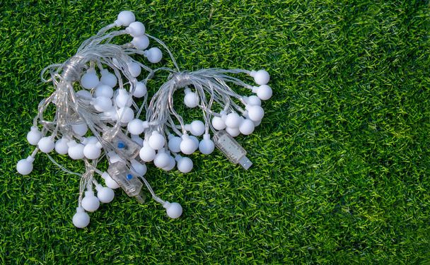Festive electric light garland on green grass background. Party garland decoration concept. Top view, copy space. - Foto, Imagen
