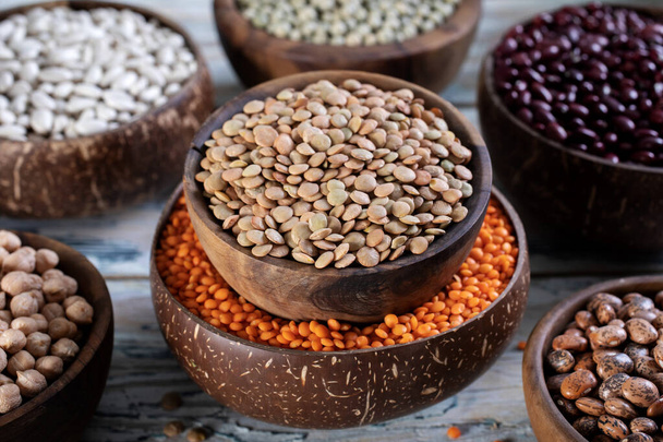 different types of legumes lentils in bowls on wooden background - Fotó, kép