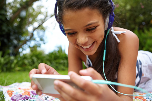 Zábava pro všechny. mladá dívka poslouchající hudbu na svém mobilu ve venkovním prostředí - Fotografie, Obrázek