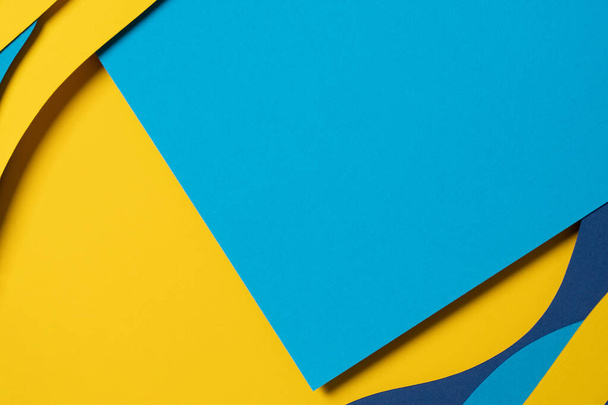 Αφηρημένο χρωματιστό χαρτί υφή φόντο. Ελάχιστη σύνθεση κοπής χαρτιού με στρώματα γεωμετρικών σχημάτων και γραμμών σε γαλάζιο, ναυτικό μπλε, κίτρινο χρώμα. - Φωτογραφία, εικόνα