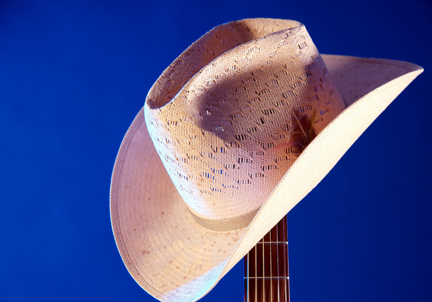 Western hat on Guitar Neck Against Blue - Photo, Image