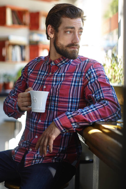 Kawa jest zaproszeniem do życia. młody człowiek trzymający filiżankę kawy w kawiarni - Zdjęcie, obraz